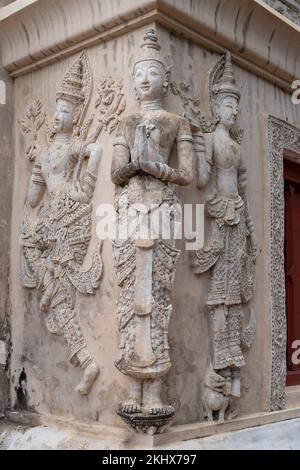 Belle figure in stucco a grandezza naturale sulla parete della biblioteca di hor trai nel tempio buddista di Wat Phra Singh, punto di riferimento di Chiang mai, Thailandia Foto Stock
