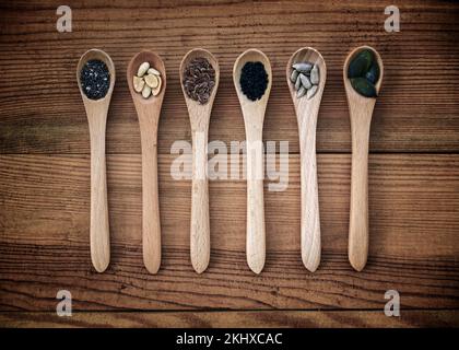 Set di semi organici in cucchiai su sfondo di legno, cibo naturale sano e concetto di nutrizione Foto Stock