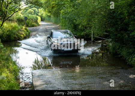 una macchina di famiglia che guida attraverso un ford Foto Stock