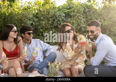 scena di gente sorridente, bevendo coktail e brinzando felicemente, festa elegante all'aperto di un lavoro di squadra di piccola agenzia di affari Foto Stock