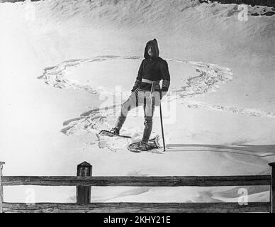 Una fotografia in bianco e nero dei primi anni del 20th che mostra un uomo che indossa scarpe da neve e abiti caldi che posa su una zona innevata nelle Alpi francesi. Foto Stock