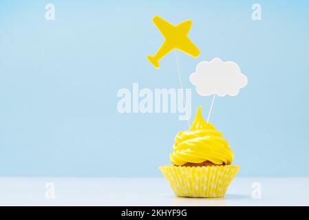 Cupcake giallo crema con decor su sfondo blu con spazio copia Foto Stock