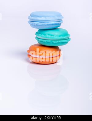 Tre macaron di tre colori diversi impilati in modo non simmetrico, su sfondo bianco Foto Stock