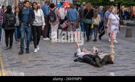 I turisti sconcertati aggirano gli artisti che si trovano nel mezzo del Royal Mile a Edimburgo per promuovere il loro Fringe Show "Bittersweet" Foto Stock