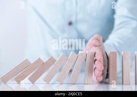 Mano d'uomo d'affari che ferma l'effetto domino per la gestione e la soluzione , la strategia concettuale e l'intervento riuscito Foto Stock