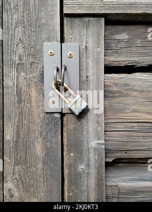Primo piano di un lucchetto stagionato su una vecchia porta di legno Foto Stock