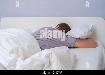 Un giovane bearded dorme in un letto comodo. Felice di dormire. Sonno sano di un uomo in un fresco letto bianco. Foto Stock