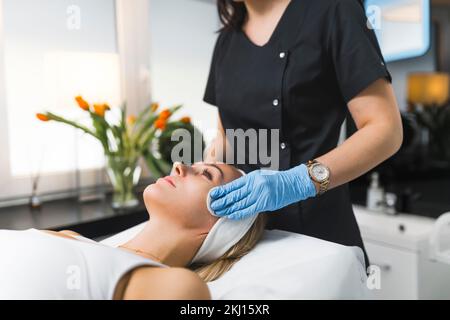 bella donna bionda su un tavolo con trattamento spa da parte di una massaggiatrice al centro benessere, spa e concetto di cura della pelle. Foto di alta qualità Foto Stock