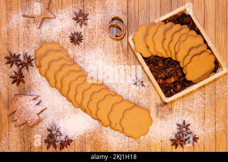 Il biscotto di pan di zenzero si trova su uno sfondo di legno, cosparso di zucchero a velo Foto Stock