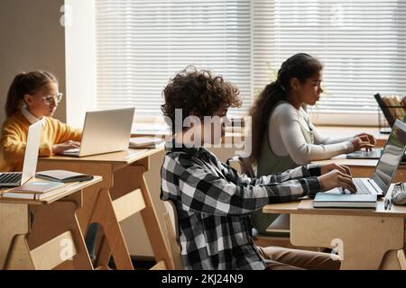 Gruppo di bambini che imparano a lavorare con il programma informatico durante la lezione DI INFORMATICA in aula Foto Stock