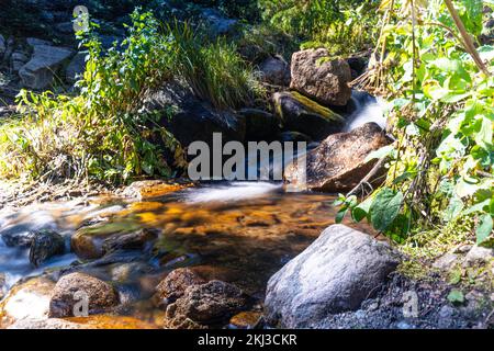 Un'acqua effetto seta che scorre lungo un fiume roccioso Foto Stock