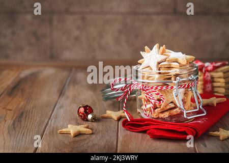 Biscotti di Natale o stelle di pan di zenzero con nastro rosso, decorazione festosa, abete, palle e ghirland leggero. Biscotti tradizionali tedeschi. C Foto Stock
