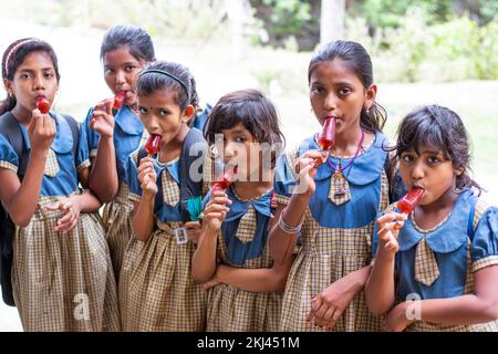 Scuola i bambini mangiano un lolly di ghiaccio all'aperto Foto Stock