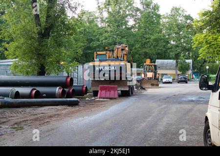 Bielorussia, Novopolotsk - 01 agosto 2022: Escavatori e tubi sull'erba in estate Foto Stock