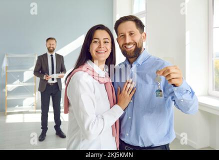Ritratto di felice giovane famiglia caucasica con gioia e contentedly mostrando le chiavi alla loro nuova casa. Foto Stock