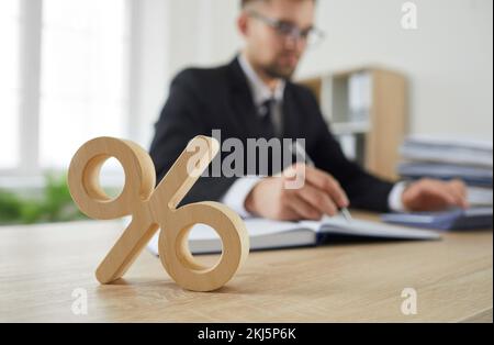 Primo piano di segno di legno percentuale sul tavolo come simbolo di imposta societaria e tasso di interesse. Foto Stock