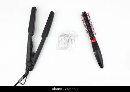 Pettine e piastra per capelli ferro arricciacapelli elettrico con piastre in ceramica e perdita di capelli neri su sfondo bianco. Capelli lisci Foto Stock