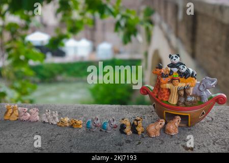 Piccole figurine in ceramica rianimano gli animali che si allineano in coppia per entrare nell'Arca di Noè. Illustrazione della storia della Bibbia carina e adatta ai bambini. Genesi inondazione narrativa. Foto Stock