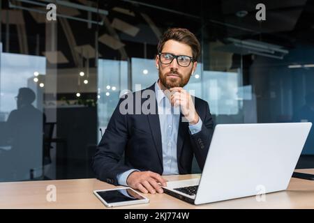 Maturo serio uomo d'affari pensiero che lavora all'interno dell'ufficio, investitore boss in tuta di affari che lavora al tavolo con laptop brainstorming strategia di affari e piano. Foto Stock