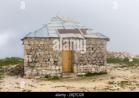 Antica chiesa ortodossa di San Giorgi in pietra a Khvamli catena montuosa in Georgia, edificio trascurato con tetto in lamiera, tempo nebbia. Foto Stock