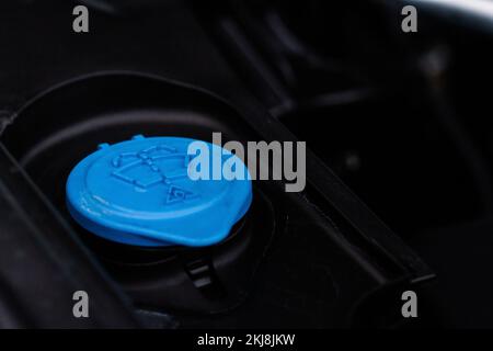 Chiudere il tappo blu del serbatoio del liquido lavavetro nel vano motore. Tappi liquidi all'interno del motore di un'auto. Tappo del serbatoio del liquido lavavetro. Foto Stock