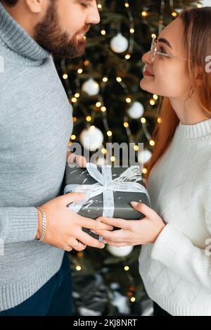 Coppia carina, giovane che scambiano i regali di Natale per la mattina di Natale Foto Stock