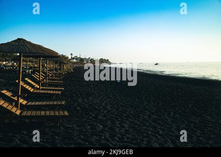 Seascape e Chaise lounge spiaggia nera di Kamari a Santorini Foto Stock