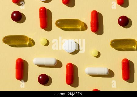 Composizione di una varietà di pillole e capsule su sfondo giallo Foto Stock