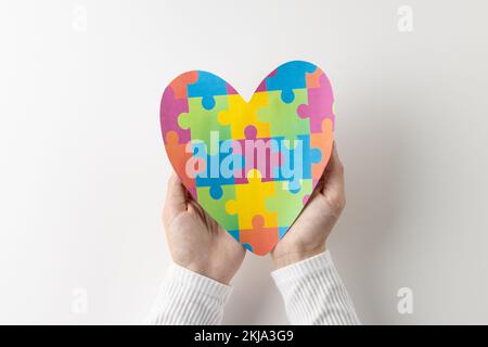 Composizione di mani che tengono il cuore puzzle puzzle jigsaw su sfondo bianco con spazio copia Foto Stock