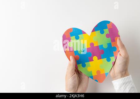 Composizione di mani che tengono il cuore puzzle puzzle jigsaw su sfondo bianco con spazio copia Foto Stock