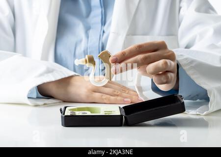 Sezione centrale di una dottoressa caucasica in possesso di apparecchi acustici Foto Stock