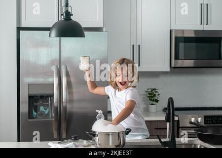 Divertenti ragazzi gemelli che aiutano in cucina con piatti di lavaggio. Bambini che si divertono con i lavori di casa. Aiuto per bambini nel lavaggio dei piatti in cucina. Foto Stock