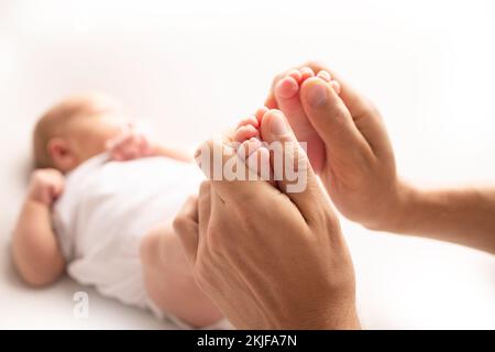 La madre sta facendo il massaggio sul suo piede del bambino. Avvicinate i piedi del bambino nelle mani della madre. Foto Stock