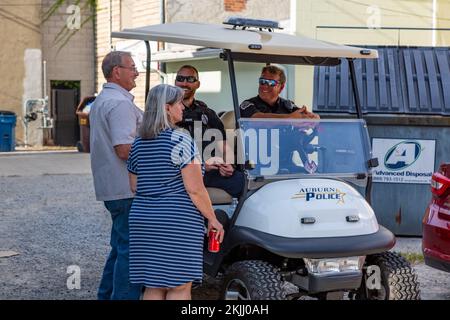 Gli ufficiali del Dipartimento di polizia di Auburn siedono in un golf cart Club Car contrassegnato mentre interagiscono con una coppia ad Auburn, Indiana, USA. Foto Stock