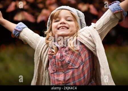 I bambini hanno un modo speciale di aggiungere gioia a ogni giorno. una bambina carina che si gode una giornata autunnale in giardino. Foto Stock