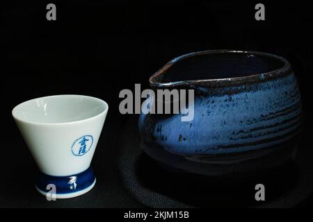 Bottiglia di sakè blu giapponese e tazza bianca illuminata su un vassoio nel ristorante kyoto, giappone Foto Stock