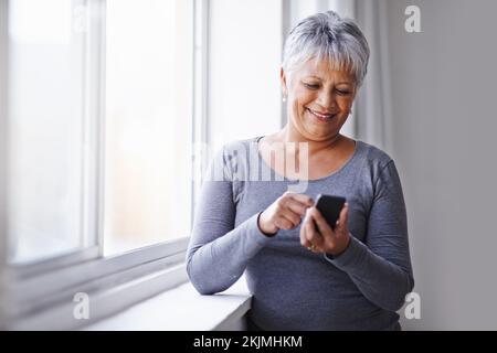 Goditi la vista. una donna matura che usa il cellulare a casa. Foto Stock