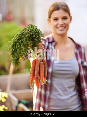 Qui non ci sono sostanze chimiche. una giovane donna felice che tiene un mazzo di carote appena raccolte. Foto Stock