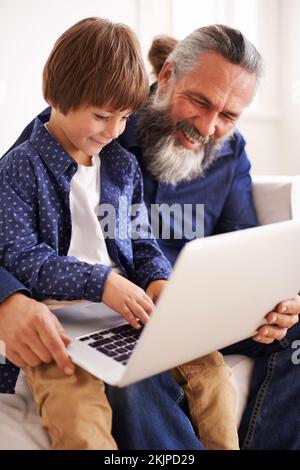 Aiutare il nonno con il notebook. un nonno e un nipote che utilizzano un notebook insieme. Foto Stock