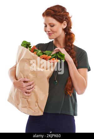 Hmmm... Che cosa intendo fare con questi. Studio shot di una bella giovane donna in possesso di una borsa per la spesa piena di verdure fresche. Foto Stock