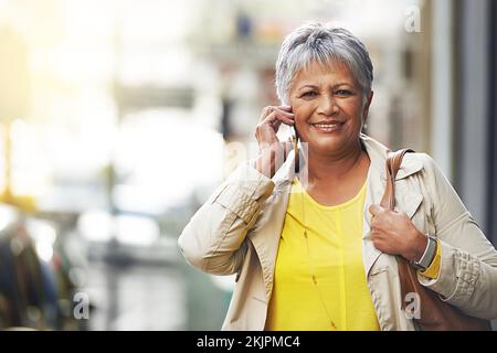 Vai dove ti portano i piedi. una donna matura che parla sul suo cellulare in città. Foto Stock