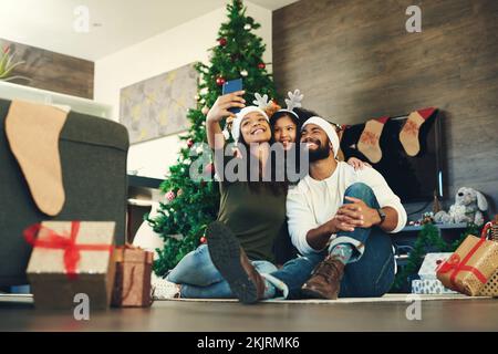 Famiglia, selfie e festeggiamenti natalizi con un uomo, una donna e un bambino entusiasti di una foto di famiglia per le feste. Natale, regalo e foto per cellulare Foto Stock