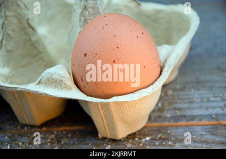 Un uovo di pollo marrone macinato in scatola su un tavolo di legno Foto Stock