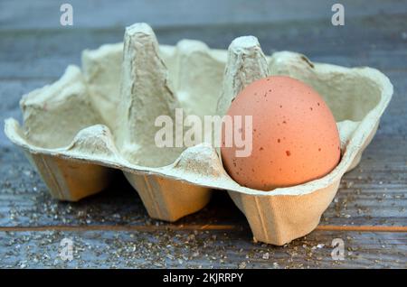 Un uovo di pollo marrone macinato in scatola su un tavolo di legno Foto Stock