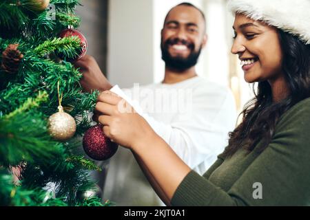Natale, amore e coppia che decorano insieme l'albero di Natale per le feste, la festa di festa e la vacanza. Legame, matrimonio e uomo felice e. Foto Stock