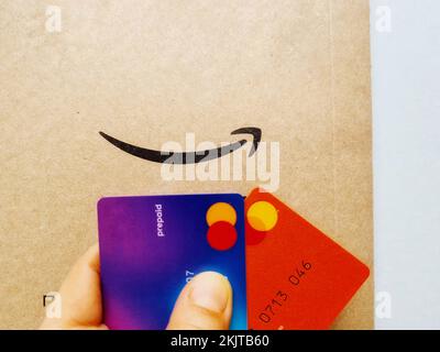 Una persona in possesso di carte di credito per il pagamento di acquisti online su Amazon Foto Stock