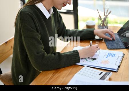 Una bella giovane donna d'affari o contabile femminile woking alla sua scrivania, la gestione delle sue attività finanziarie, l'analisi dei conti di vendita. immagine ritagliata Foto Stock