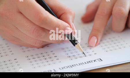 Mano femmina che tiene la matita scrittura scelta selezionata su carta di risposta Foto Stock