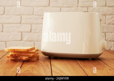 Tostapane bianco con fette di pane e una tazza di caffè sul tavolo, primo  piano Foto stock - Alamy