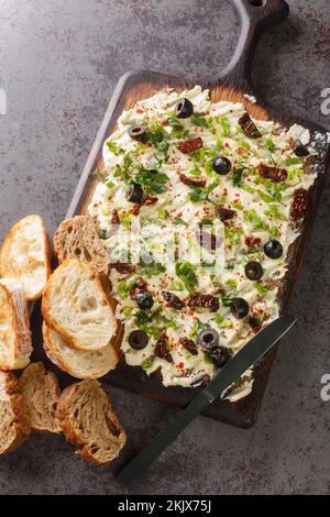 Panetteria alla moda fatta in casa con erbe, olive, pomodori secchi e primo piano di pane sul tavolo. Vista verticale dall'alto Foto Stock